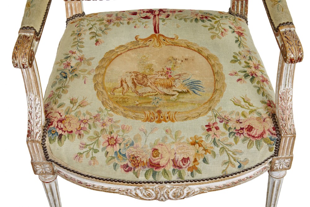 A five-piece French giltwood salon suite comprising four carved armchairs and a matching sofa, all upholstered in cream woven tapestry with floral and figurative medallions. View X