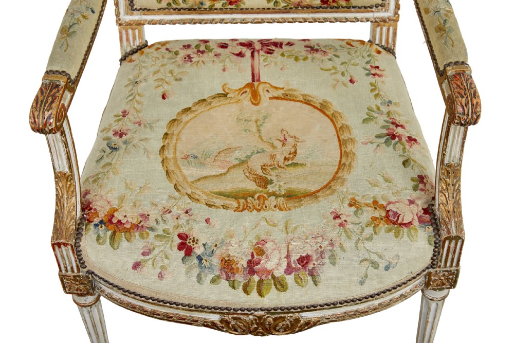 A five-piece French giltwood salon suite comprising four carved armchairs and a matching sofa, all upholstered in cream woven tapestry with floral and figurative medallions. View XII
