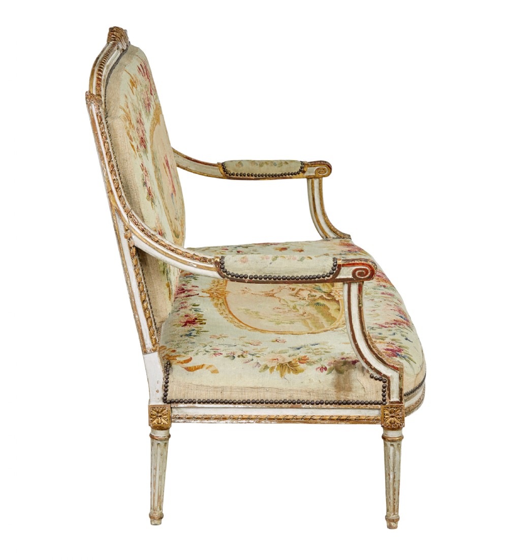 A five-piece French giltwood salon suite comprising four carved armchairs and a matching sofa, all upholstered in cream woven tapestry with floral and figurative medallions. View XVIII