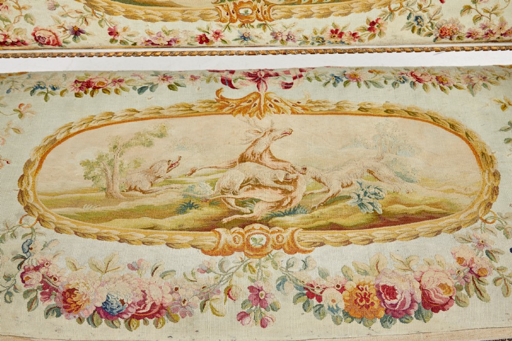 A five-piece French giltwood salon suite comprising four carved armchairs and a matching sofa, all upholstered in cream woven tapestry with floral and figurative medallions. View XXI