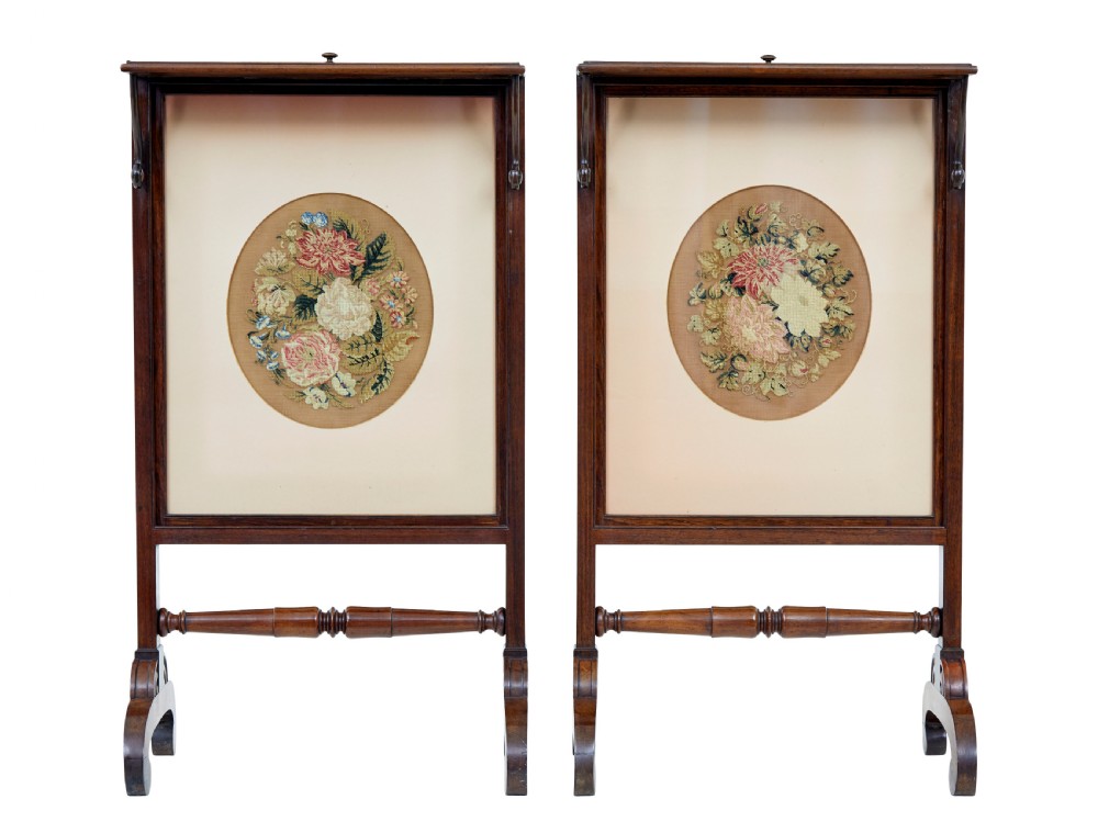 A pair of Regency palisander fire screens with turned stretchers, splayed scroll feet, and central oval floral needlepoint panels. View IV