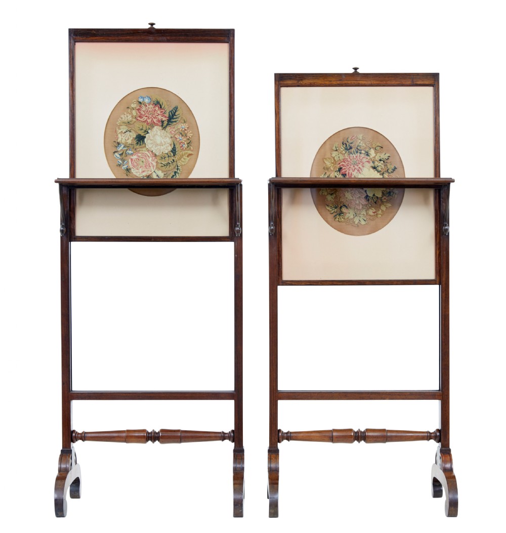 A pair of Regency palisander fire screens with turned stretchers, splayed scroll feet, and central oval floral needlepoint panels. View V