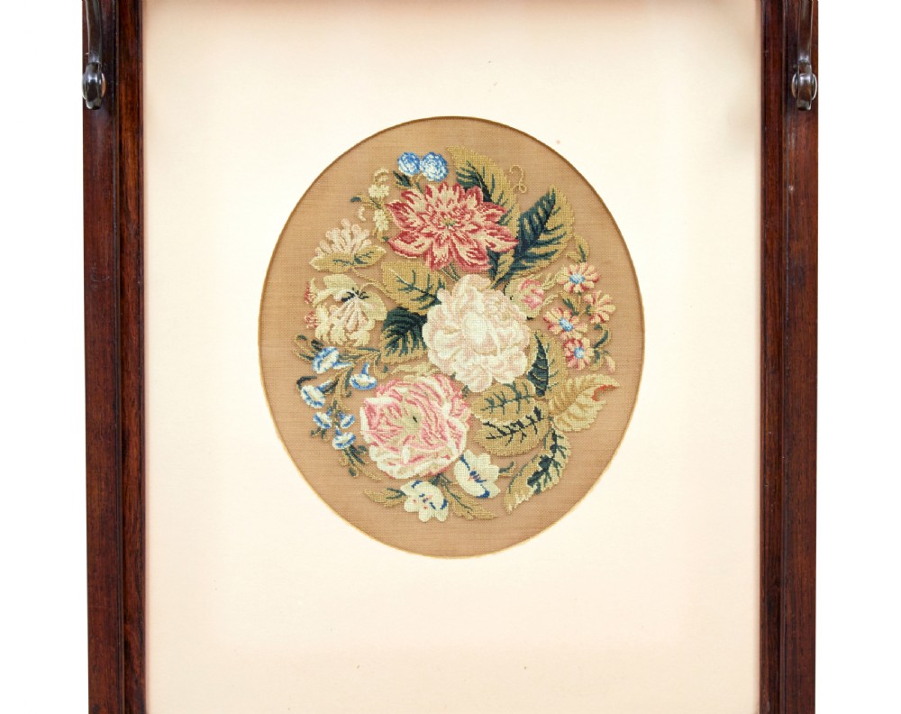 A pair of Regency palisander fire screens with turned stretchers, splayed scroll feet, and central oval floral needlepoint panels. View IX