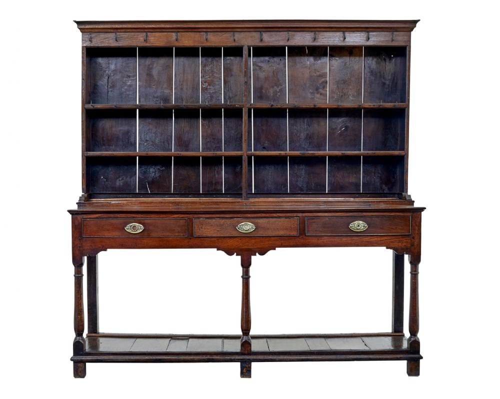 An early nineteenth-century Welsh oak dresser featuring a tall open plate rack with hooks above a three-drawer base supported by turned front legs and a lower pot board. View II