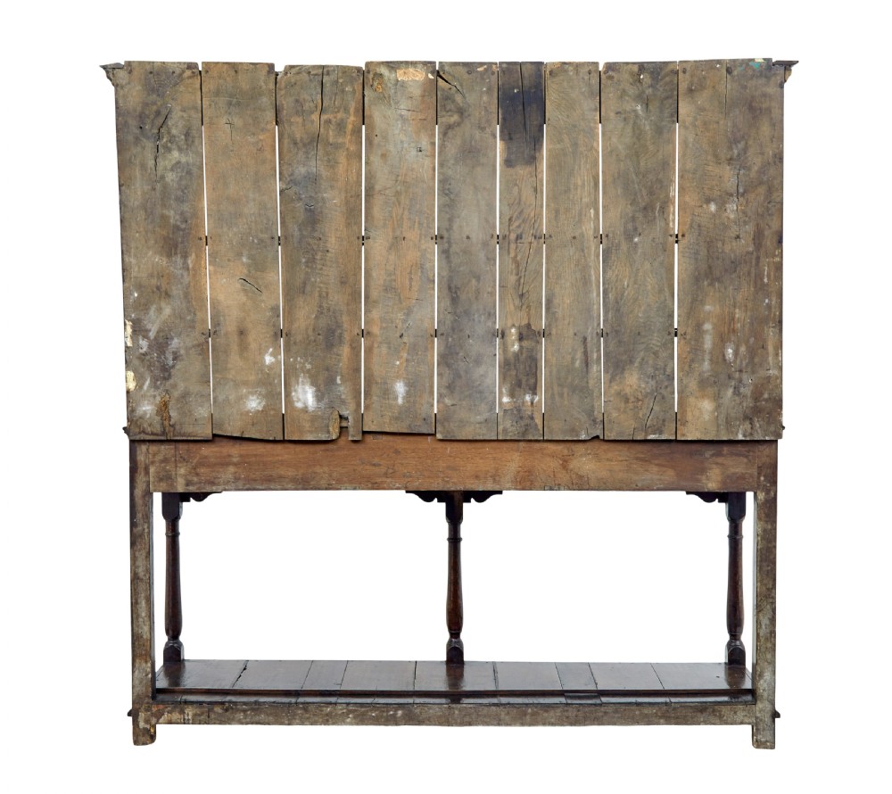 An early nineteenth-century Welsh oak dresser featuring a tall open plate rack with hooks above a three-drawer base supported by turned front legs and a lower pot board. View VI