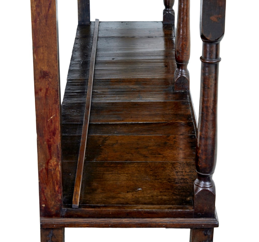 An early nineteenth-century Welsh oak dresser featuring a tall open plate rack with hooks above a three-drawer base supported by turned front legs and a lower pot board. View VII