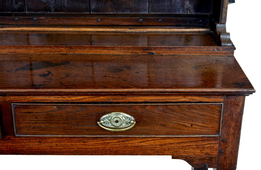 An early nineteenth-century Welsh oak dresser featuring a tall open plate rack with hooks above a three-drawer base supported by turned front legs and a lower pot board. View IX