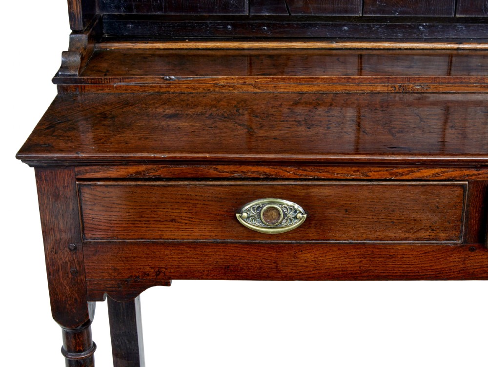 An early nineteenth-century Welsh oak dresser featuring a tall open plate rack with hooks above a three-drawer base supported by turned front legs and a lower pot board. View X