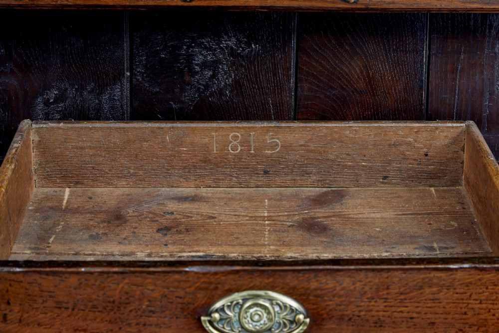 An early nineteenth-century Welsh oak dresser featuring a tall open plate rack with hooks above a three-drawer base supported by turned front legs and a lower pot board. View XI