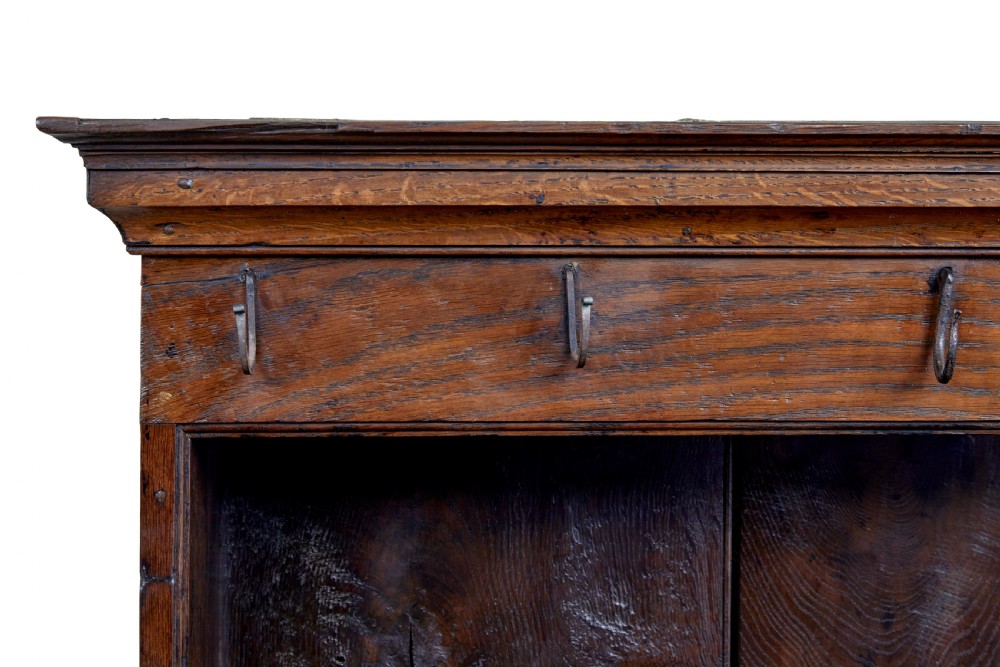 An early nineteenth-century Welsh oak dresser featuring a tall open plate rack with hooks above a three-drawer base supported by turned front legs and a lower pot board. View XII