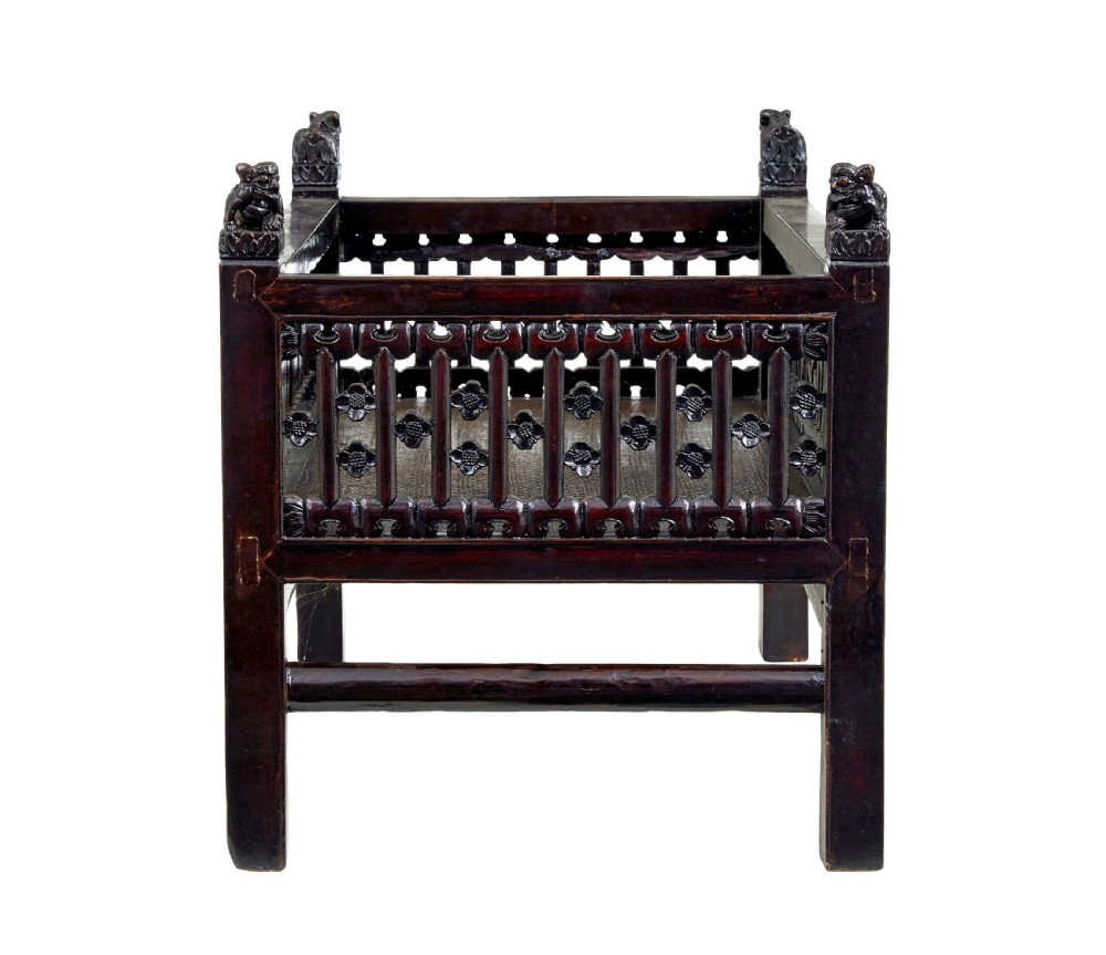 A 19th-century dark lacquered Chinese childs bed featuring carved lattice sides and guardian lion corner finials. View IV