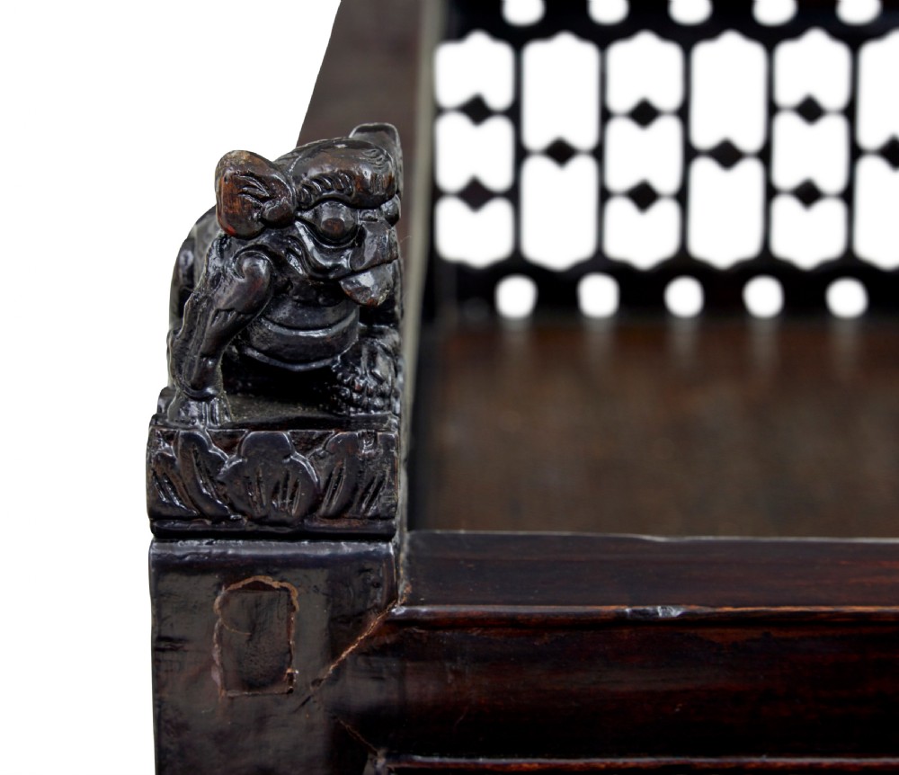 A 19th-century dark lacquered Chinese childs bed featuring carved lattice sides and guardian lion corner finials. View VIII
