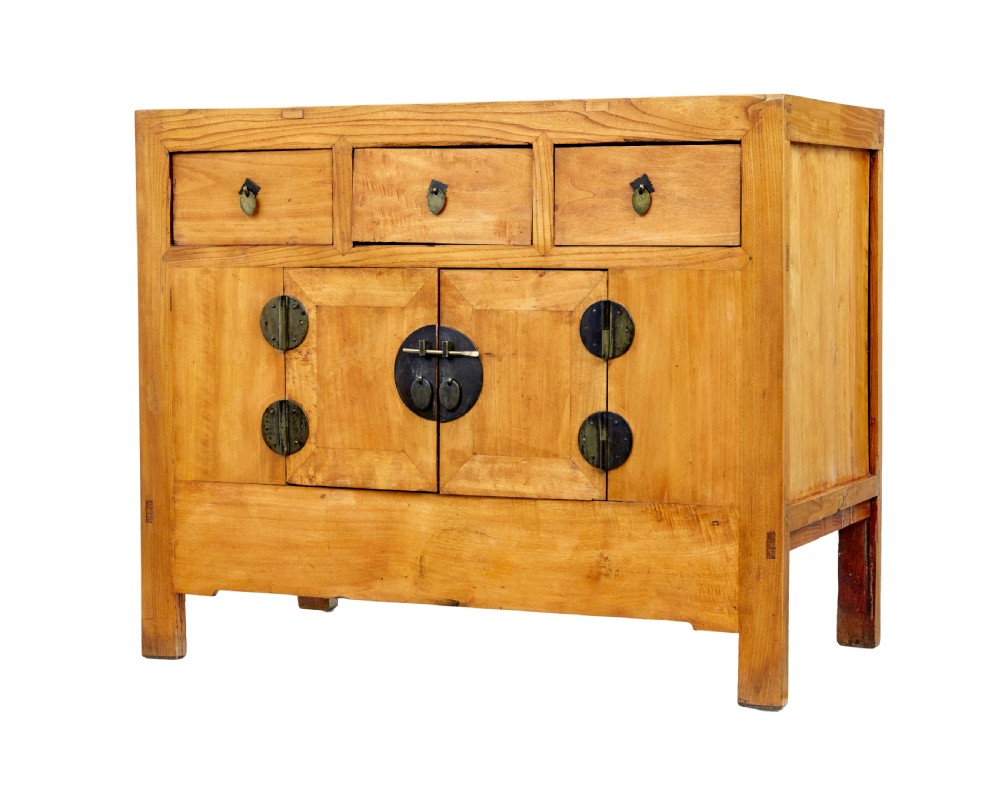 A late nineteenth-century light wood Chinese sideboard featuring three upper drawers over a double-door cupboard with circular brass faceplates.