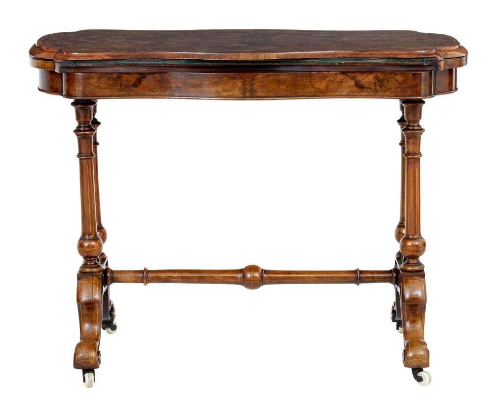 A 19th-century Victorian walnut fold-over card table featuring turned dual pedestal legs, a central stretcher rail, scroll feet, and ceramic castors. View IV