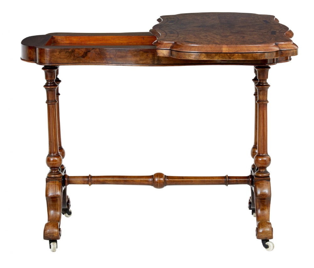 A 19th-century Victorian walnut fold-over card table featuring turned dual pedestal legs, a central stretcher rail, scroll feet, and ceramic castors. View V