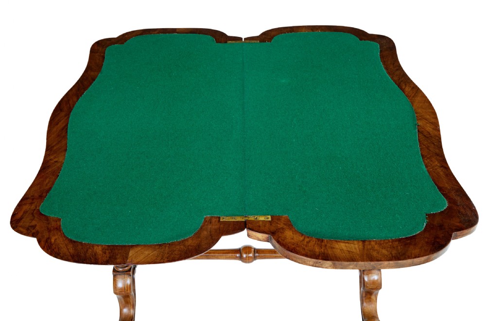 A 19th-century Victorian walnut fold-over card table featuring turned dual pedestal legs, a central stretcher rail, scroll feet, and ceramic castors. View VII