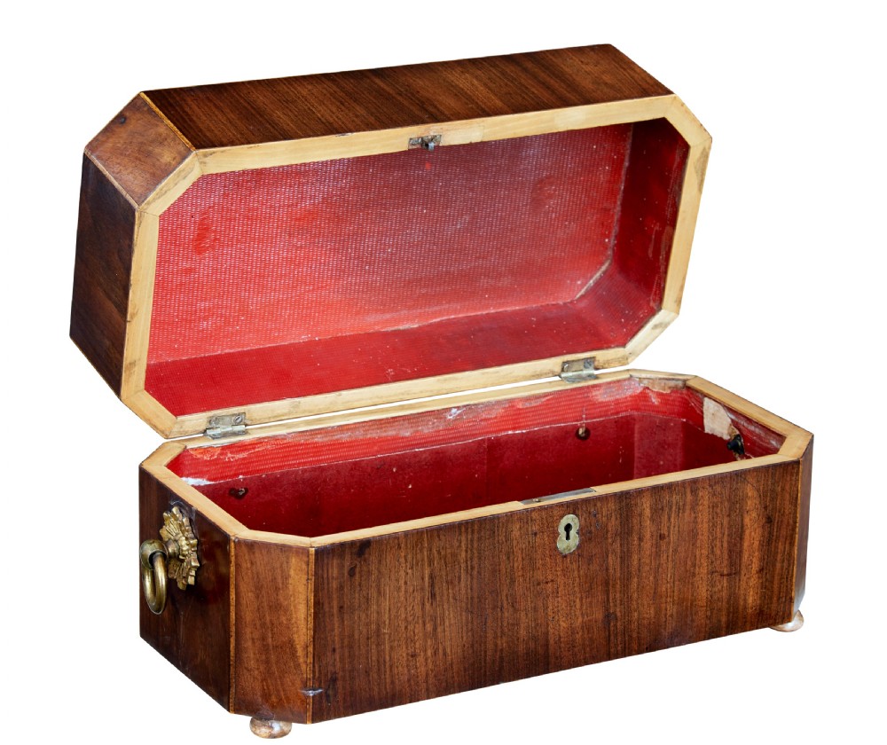 An early 19th-century mahogany tea caddy featuring a canted octagonal shape, brass side ring handles, a brass keyhole escutcheon, and bun feet. View II