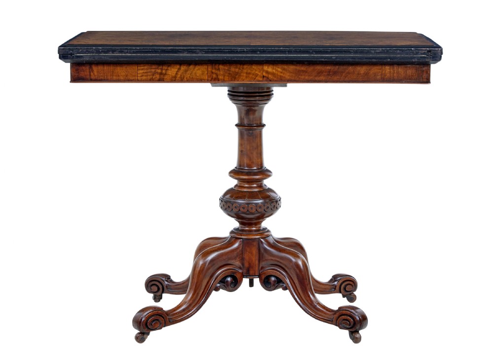A 19th-century carved walnut fold-over card table featuring an ebonised top edge, a turned central stem, and four carved scroll feet with castors. View II