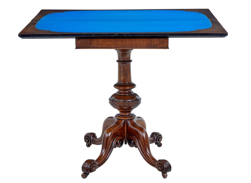 A 19th-century carved walnut fold-over card table featuring an ebonised top edge, a turned central stem, and four carved scroll feet with castors. View IV