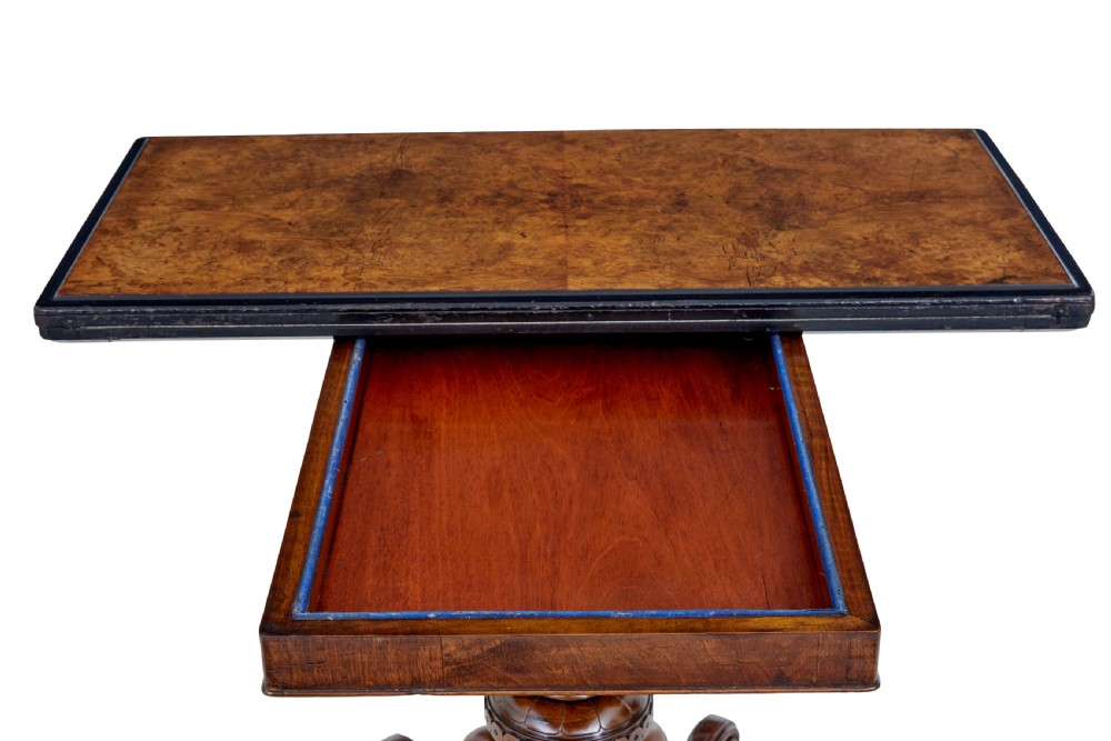 A 19th-century carved walnut fold-over card table featuring an ebonised top edge, a turned central stem, and four carved scroll feet with castors. View VI