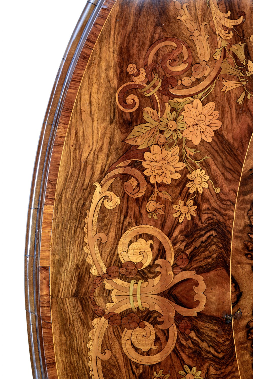 A 19th-century oval walnut tilt-top table with intricate floral marquetry inlay and a carved pedestal base with brass castors. View V