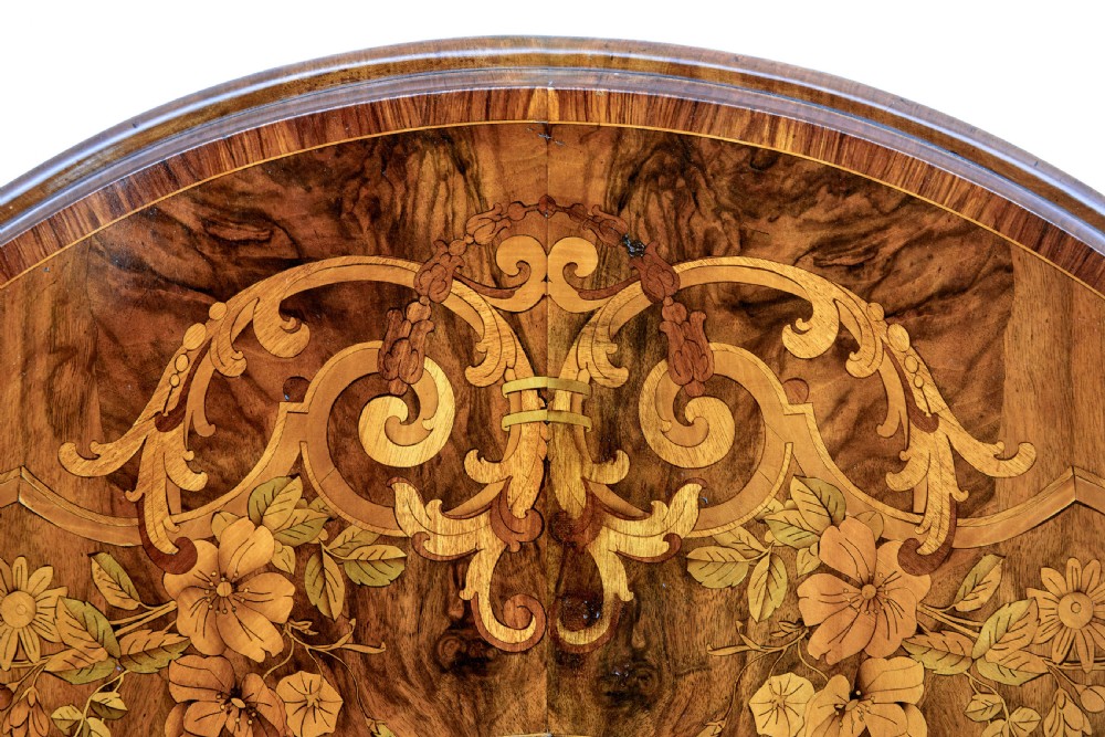 A 19th-century oval walnut tilt-top table with intricate floral marquetry inlay and a carved pedestal base with brass castors. View VII