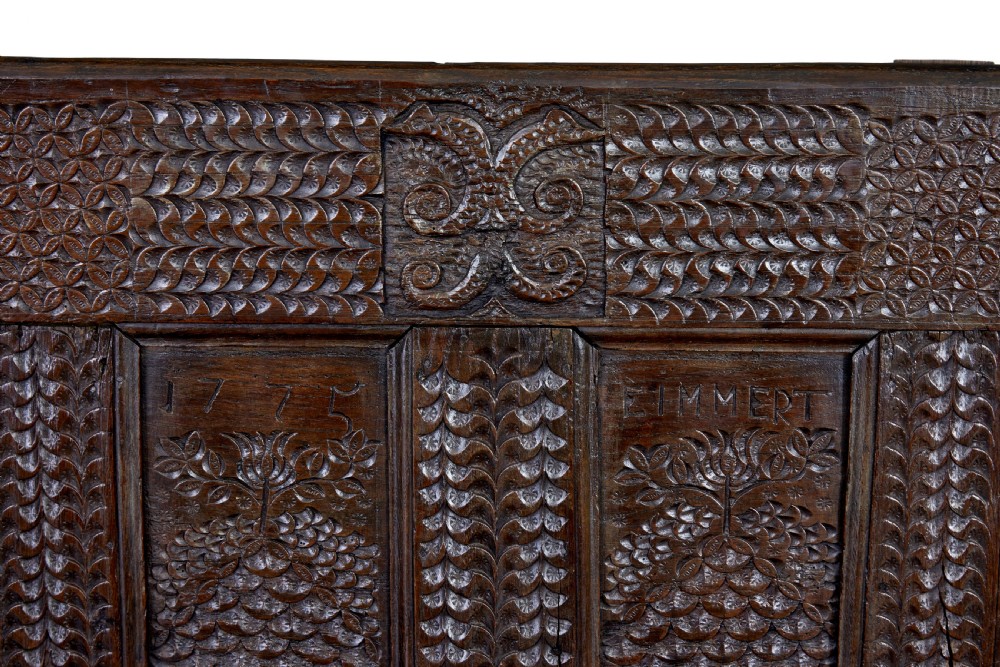 A dark carved oak bench featuring a high panelled back with intricate relief carvings and splayed trestle legs. View IX