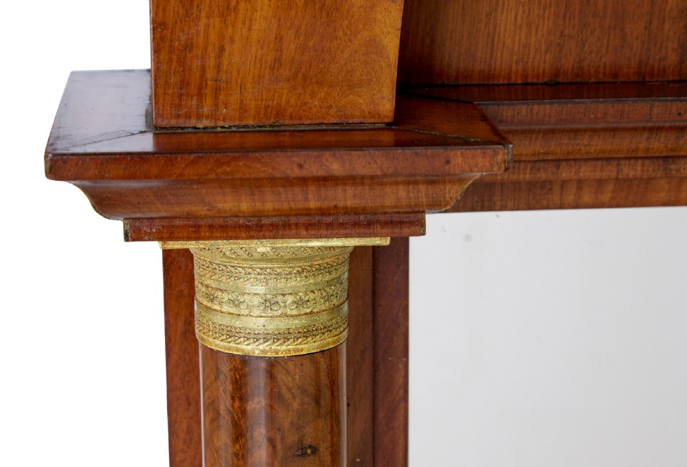 A tall nineteenth-century Empire Revival mahogany pier mirror featuring an architectural pediment, recessed arch with flame mahogany veneer, and flanking columns with gilded capitals. View V
