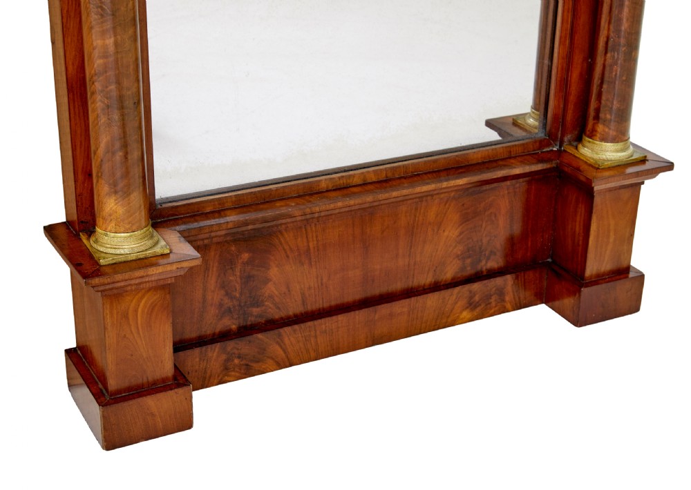 A tall nineteenth-century Empire Revival mahogany pier mirror featuring an architectural pediment, recessed arch with flame mahogany veneer, and flanking columns with gilded capitals. View VI