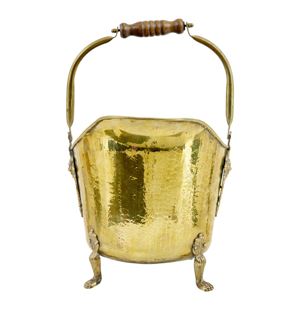 A 19th-century hammered brass helmet coal scuttle with an overhead handle, ornate side mounts, and paw feet. View III