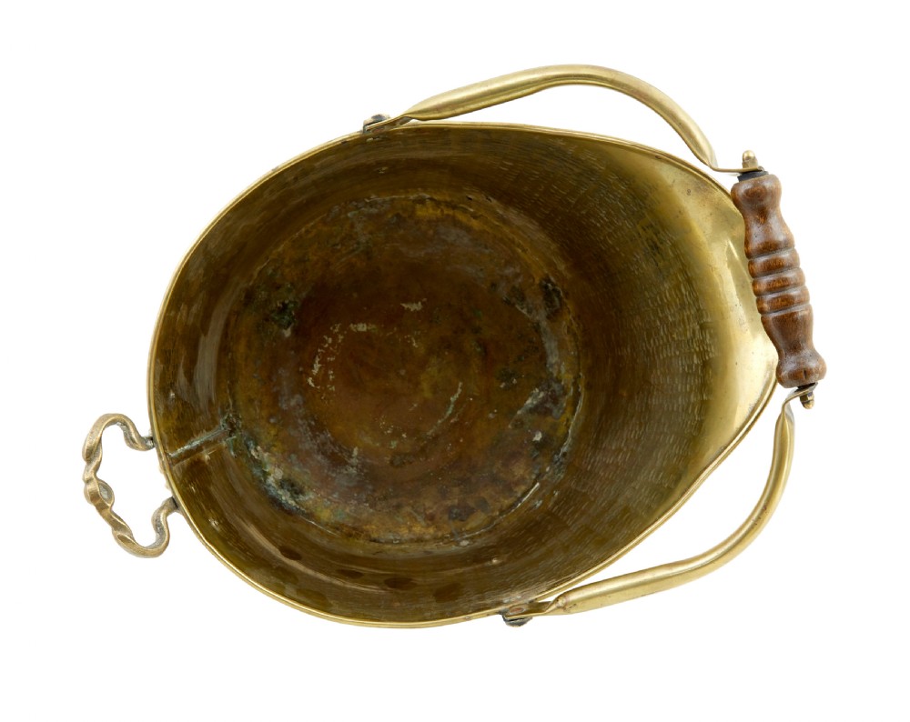 A 19th-century hammered brass helmet coal scuttle with an overhead handle, ornate side mounts, and paw feet. View V