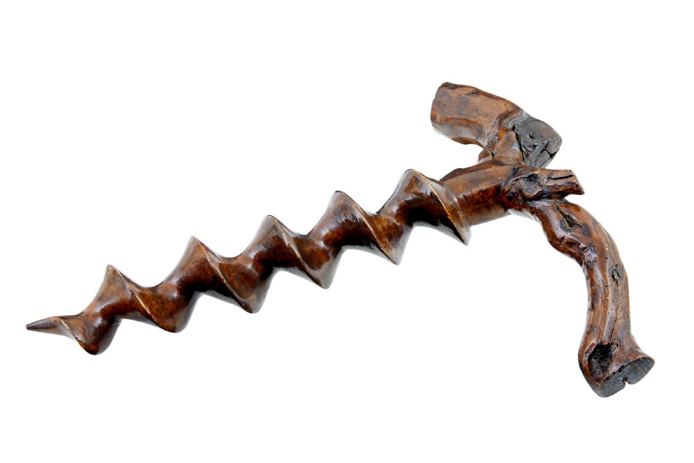 A hand-carved dark wood corkscrew featuring a carved spiral helix and an ergonomic, naturalistic wooden handle.
