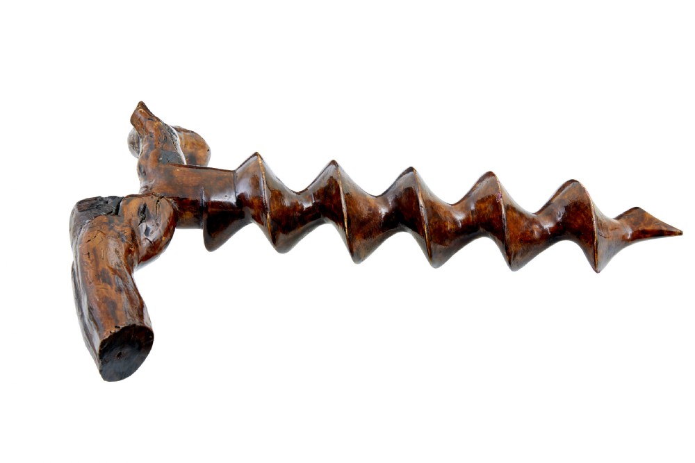 A hand-carved dark wood corkscrew featuring a carved spiral helix and an ergonomic, naturalistic wooden handle. View IV