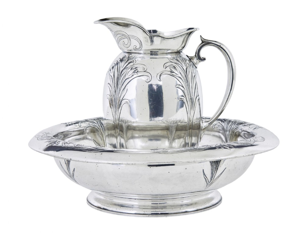 An Art Nouveau silver-plated ewer jug and matching basin set made by Christofle featuring relief-carved botanical foliage details.