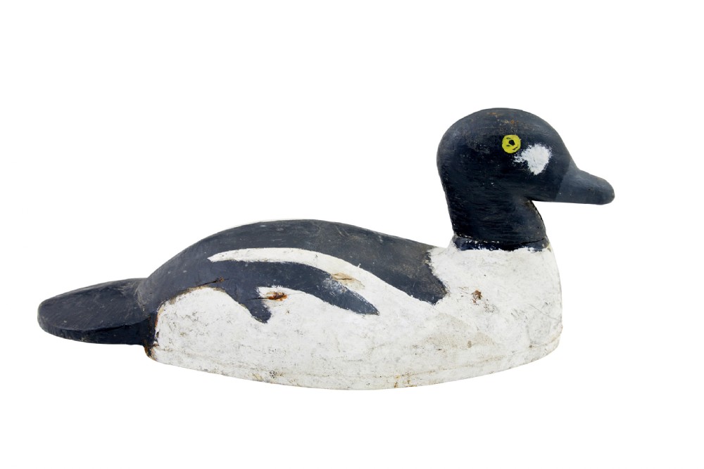 A hand-carved early 20th-century wooden duck decoy styled with distressed black and white painted finish and yellow eye detail. View II