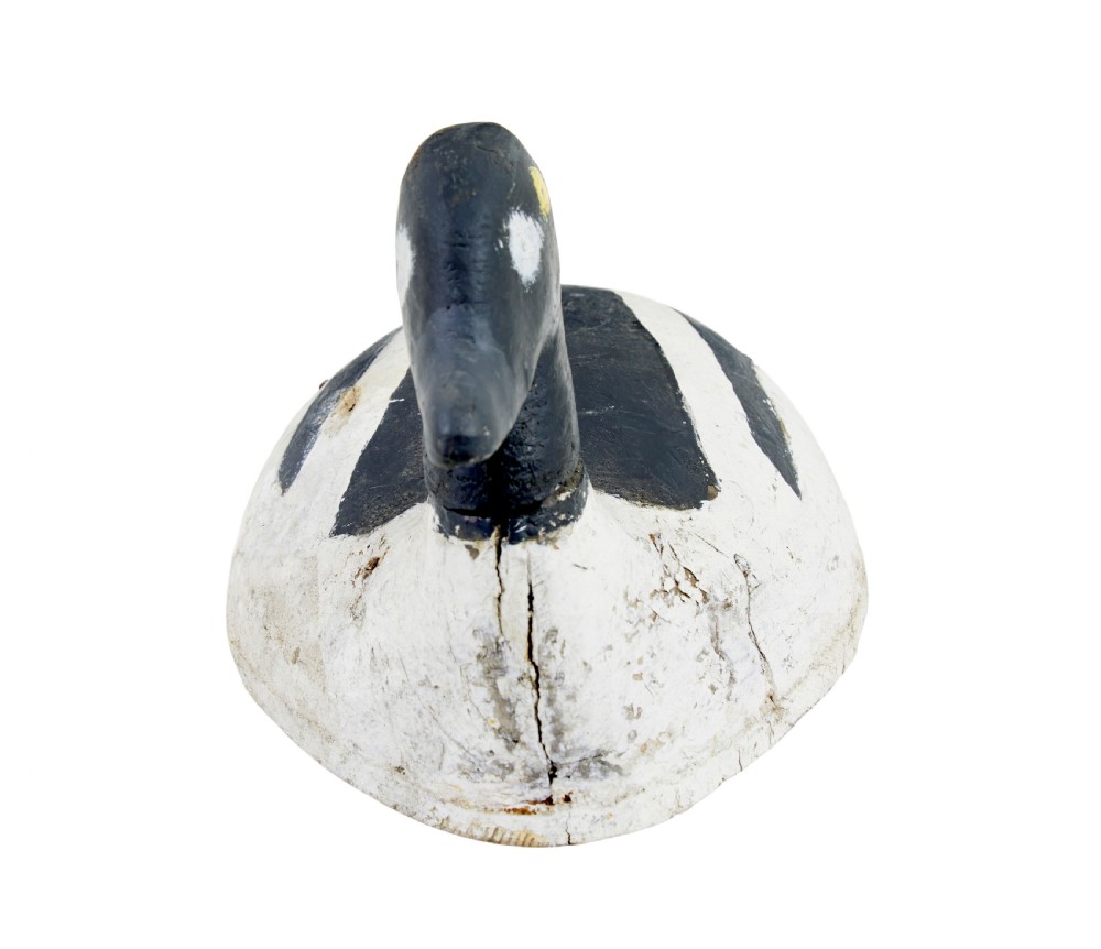 A hand-carved early 20th-century wooden duck decoy styled with distressed black and white painted finish and yellow eye detail. View III