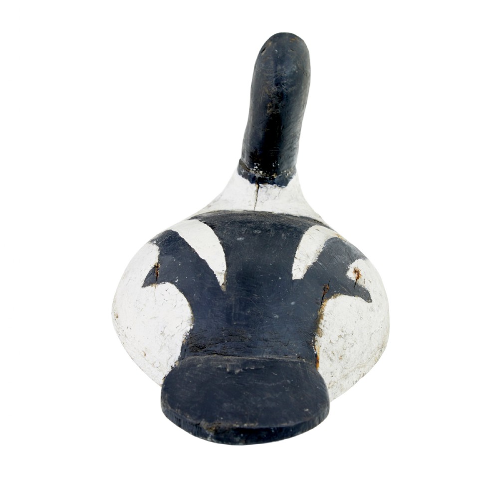 A hand-carved early 20th-century wooden duck decoy styled with distressed black and white painted finish and yellow eye detail. View IV