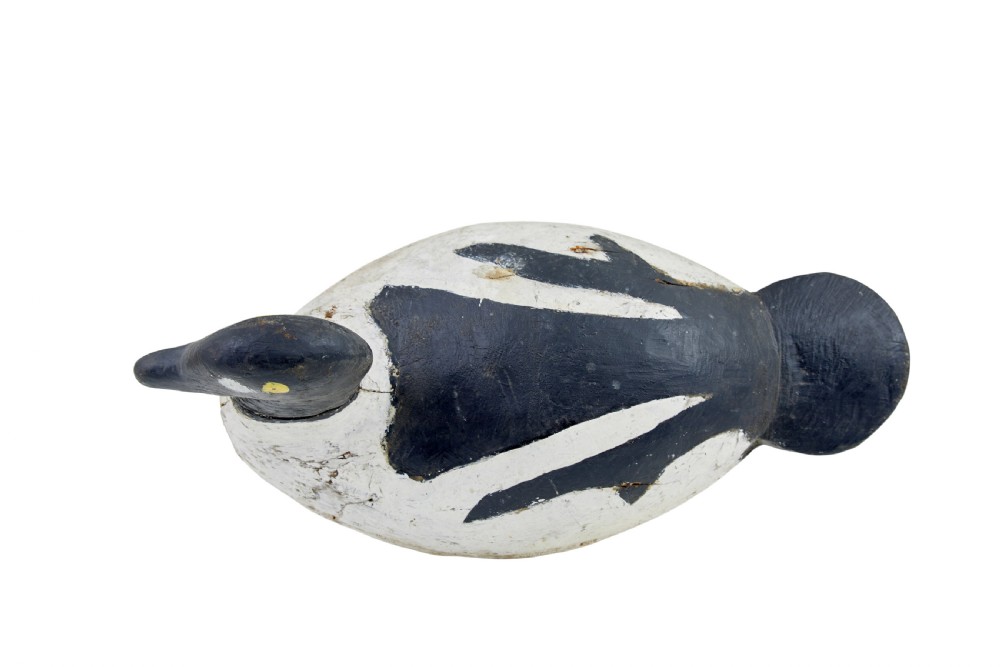 A hand-carved early 20th-century wooden duck decoy styled with distressed black and white painted finish and yellow eye detail. View VI