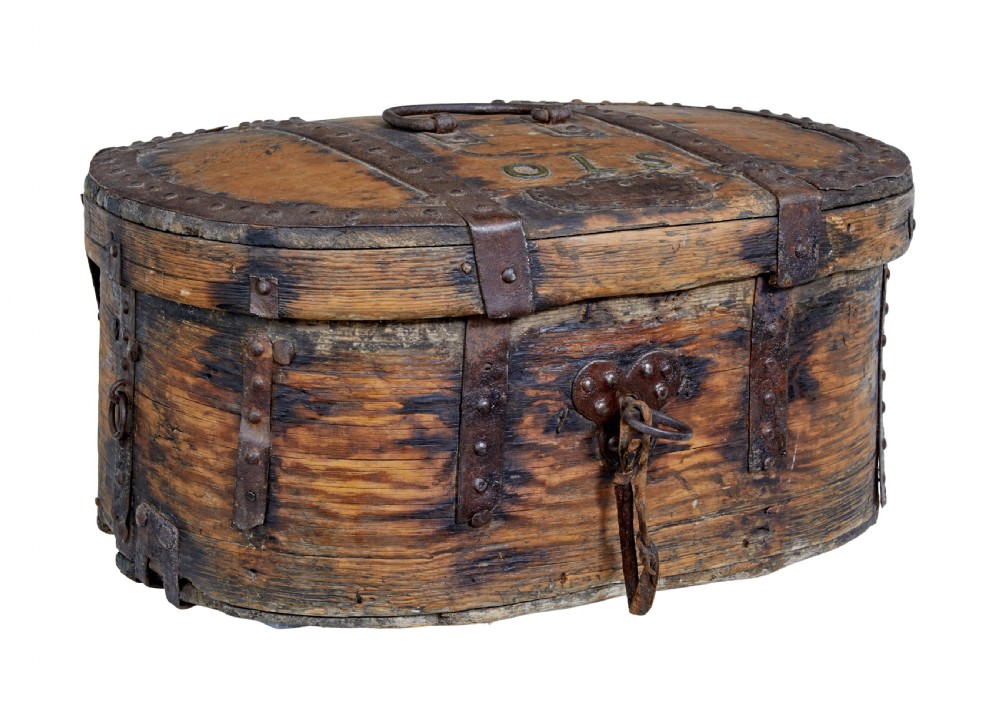 An early 18th-century Scandinavian oval oak box featuring wrought iron binding straps, studded rivets, and carved initials on the top.