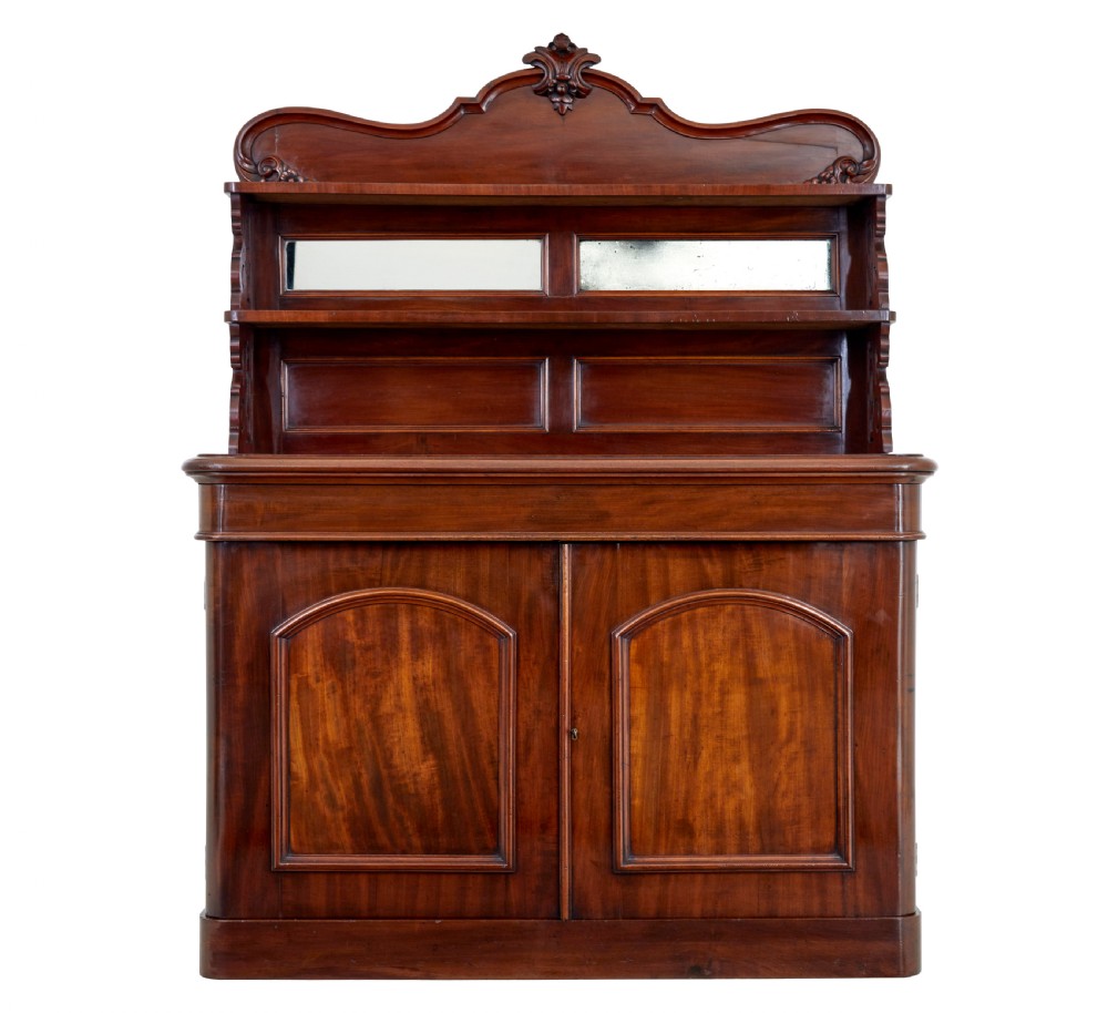 A 19th-century French mahogany chiffonier sideboard featuring a carved pediment upper tier with inset mirror panels over a two-door base cabinet.