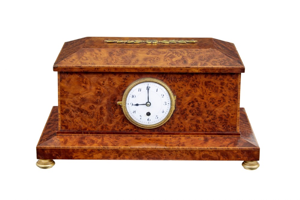 An early 20th-century burr yew desktop box featuring a circular clock face on the front, gilt brass top ornamentation, and brass feet.