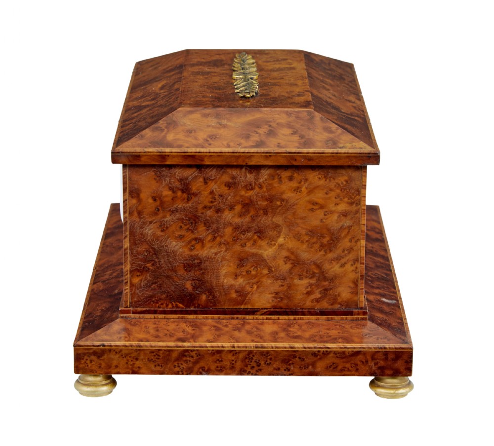 An early 20th-century burr yew desktop box featuring a circular clock face on the front, gilt brass top ornamentation, and brass feet. View III