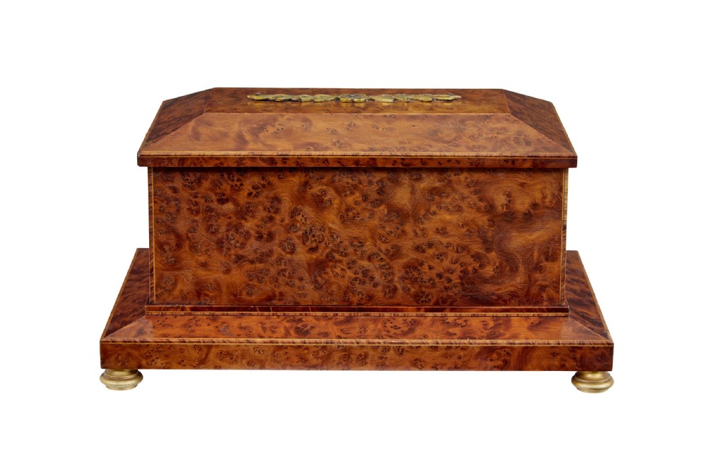 An early 20th-century burr yew desktop box featuring a circular clock face on the front, gilt brass top ornamentation, and brass feet. View IV