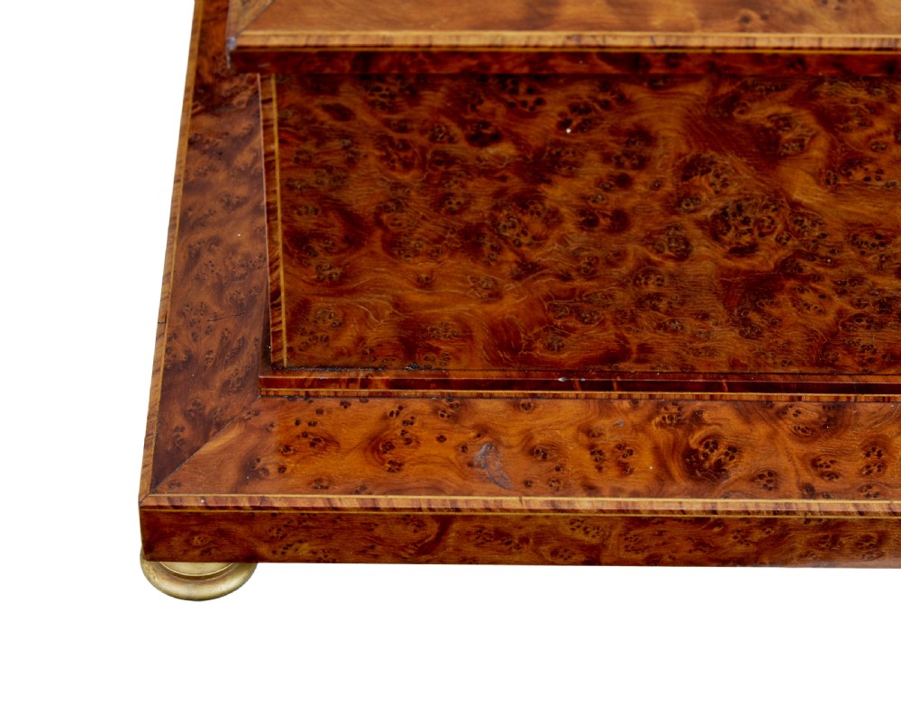 An early 20th-century burr yew desktop box featuring a circular clock face on the front, gilt brass top ornamentation, and brass feet. View IX