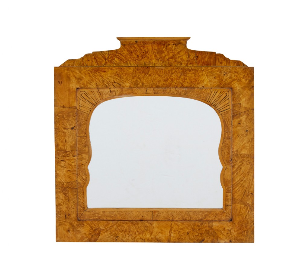A nineteenth-century Biedermeier mantle mirror featuring a figured root birch veneer frame with a stepped crest and carved fan spandrel details.