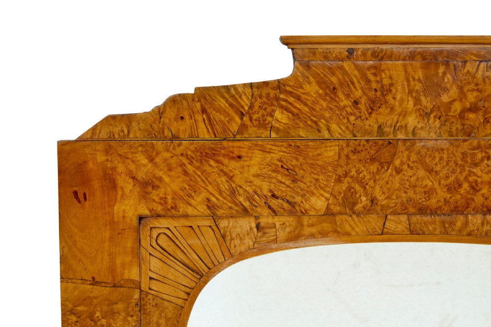 A nineteenth-century Biedermeier mantle mirror featuring a figured root birch veneer frame with a stepped crest and carved fan spandrel details. View II