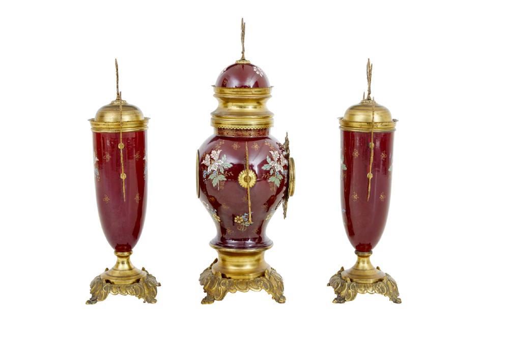 A nineteenth-century three-piece French toleware garniture set comprising a central clock urn and two matching side urns in crimson with hand-painted flowers and gilt mounts. View IV