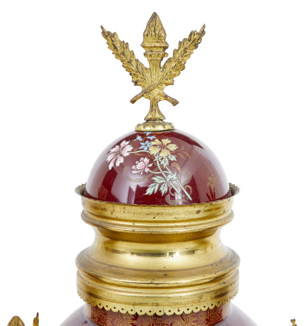 A nineteenth-century three-piece French toleware garniture set comprising a central clock urn and two matching side urns in crimson with hand-painted flowers and gilt mounts. View VII