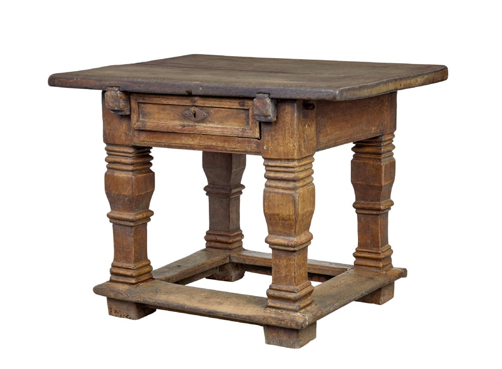 A 17th-century Flemish carved oak side table featuring a frieze drawer, turned legs, and a lower box stretcher.