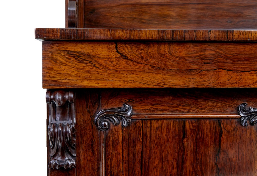 A nineteenth-century Regency palisander chiffonier sideboard with its two panelled doors open, revealing internal wooden shelves, topped with a carved scrollwork gallery shelf. View VI